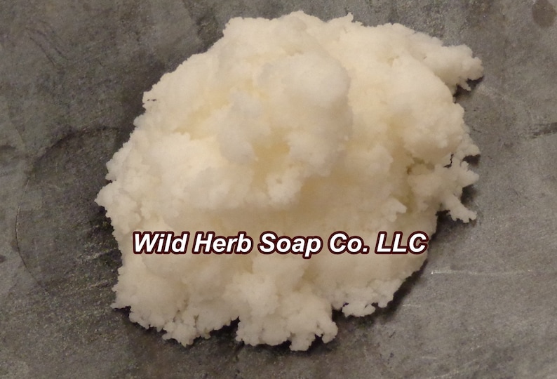 May include: A close-up of a white, fluffy, soap base. The soap base is on a gray surface. The text "Wild Herb Soap Co. LLC" is visible in the image.