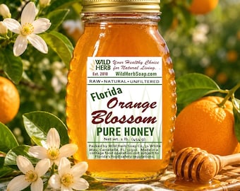 Op de afbeelding: Een glazen pot met goudkleurige Florida Orange Blossom Pure Honey met een gouden deksel. Het etiket vermeldt Wild Herb Your Healthy Choice for Natural Living, Florida Orange Blossom Pure Honey, Net wt. 1 lb. (454 g) en WildHerbSoap.com.