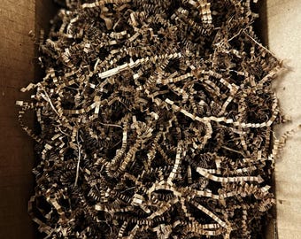 May include: A cardboard box filled with brown packing paper shreds.