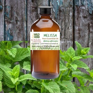May include: A brown glass bottle with a white label that reads "MELISSA Pure Essential Oil (Melissa officinalis) Ingredients: 100% Melissa essential oil. Learn more at: WildHerbSoap.com For external use."