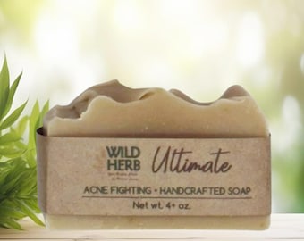 May include: A rectangular bar of beige handcrafted soap wrapped in a brown paper label. The label features the text Wild Herb Ultimate, Acne Fighting, Handcrafted Soap, and Net wt. 4+ oz. The soap has a wavy, uneven top edge.