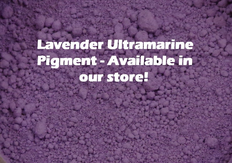 May include: Close-up of lavender ultramarine pigment. The image shows a textured, granular powder in a deep purple hue. White text on the image reads "Lavender Ultramarine Pigment - Available in our store!"