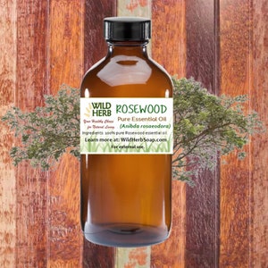 May include: A brown glass bottle with a label that reads "WILD HERB ROSEWOOD Pure Essential Oil (Anibda rosaeodora) Your Healthy Choice for Natural Living. Ingredients: 100% pure Rosewood essential oil. Learn more at: WildHerbSoap.com For external use."
