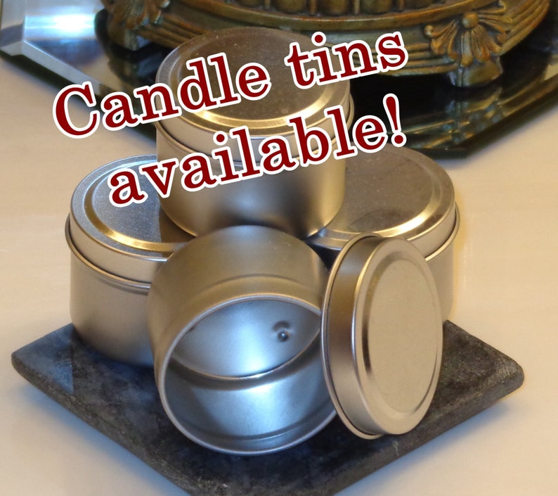 May include: A group of five silver metal candle tins, stacked on top of each other. The text "Candle tins available!" is written in red letters across the top of the image.