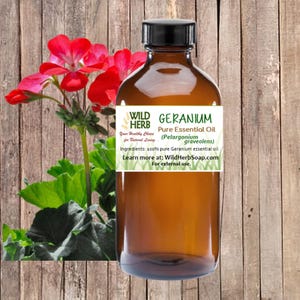 May include: A brown glass bottle with a white label that reads "WILD HERB GERANIUM Pure Essential Oil (Pelargonium graveolens) Your Healthy Choice for Natural Living Ingredients: 100% pure Geranium essential oil. Learn more at: WildHerbSoap.com For external use."
