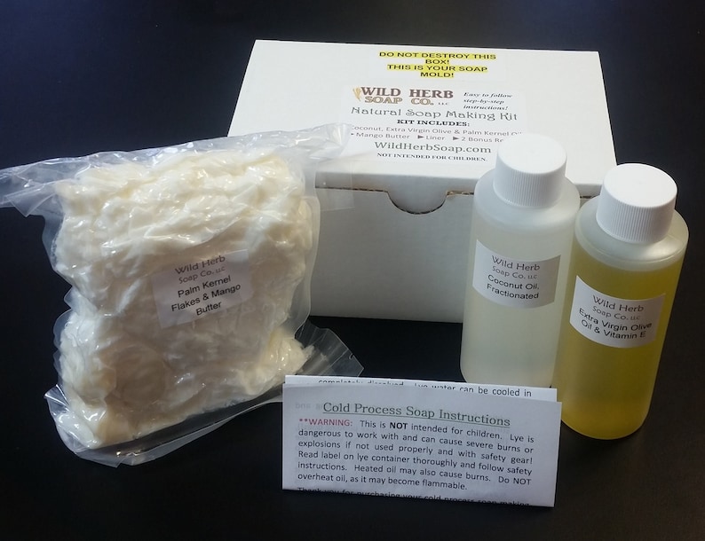 Pu&ograve; includere: Una scatola bianca con la scritta "Wild Herb Soap Co. Natural Soap Making Kit" sul davanti. La scatola contiene un sacchetto di fiocchi bianchi etichettati "Palm Kernel Flakes & Mango Butter", una bottiglia trasparente di olio di cocco e una bottiglia trasparente di olio extra vergine di oliva con vitamina E.