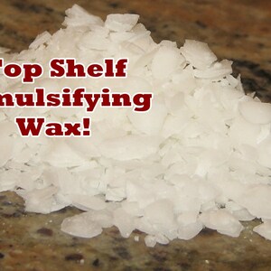 May include: A close-up of white, flaked emulsifying wax. The text "Top Shelf Emulsifying Wax!" is written in red letters on top of the wax.