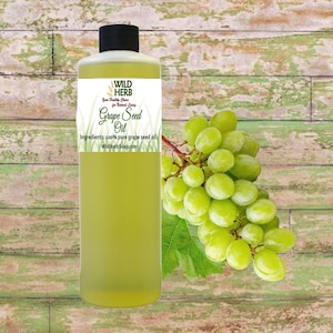 May include: A clear bottle of Wild Herb Grape Seed Oil with a black cap, a white label, and a bunch of green grapes. The label reads "Grape Seed Oil" and "Ingredients: 100% pure grape seed oil."