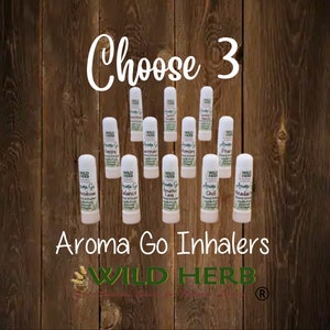May include: Choose 3 from a selection of 12 white tubes labeled "Aroma Go Inhalers" with various scents, including "Happy", "Lavender", "Balance", "Breathe Easy", "Chill", and "Headache". The tubes are arranged in a grid pattern on a wooden background. The text "WILD HERB" is displayed below the tubes.