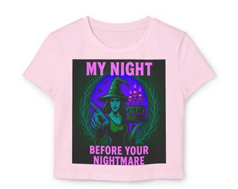 May include: Pink t-shirt with a graphic featuring a witch in a green hat and dress, pointing. The text "MY NIGHT" and "BEFORE YOUR NIGHTMARE" are in purple. The witch is holding a cake with skull candles.