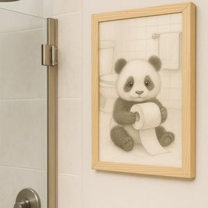 May include: A framed pencil drawing of a panda bear in a bathroom, holding a toilet roll. The panda is black and white, with a cute expression. The frame is light wood. The background shows a toilet and towel rail.