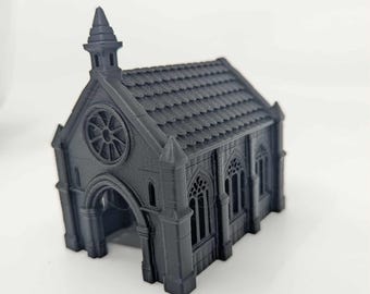 May include: A miniature, dark gray model of a gothic chapel. The chapel features a detailed roof, arched doorway, and a rose window. The structure has multiple arched windows and decorative spires, creating a detailed architectural design.