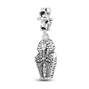 May include: A silver charm featuring an Egyptian pharaoh's sarcophagus pendant. The charm has intricate details, including the pharaoh's face and hieroglyphic designs. The charm is suspended from a top piece with an ankh symbol.