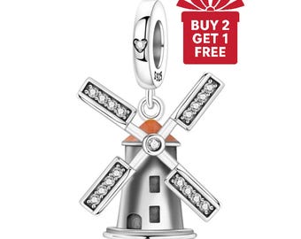 May include: A silver windmill charm with four blades adorned with clear crystals. The windmill has an orange roof and a small heart detail on the top loop. The charm is a jewelry item.