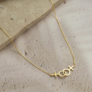 Double Venus Necklace flat lay on jewelry dish – elegant lesbian symbol necklace by Das Fine Jewelry.