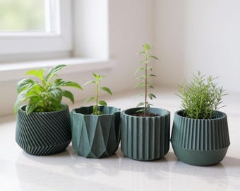 May include: Four small, dark green geometric planters with various green plants. The planters have different textured designs, including angled lines, geometric facets, and vertical ridges. The plants vary in size and type, with lush green leaves.