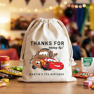 May include: A white ceramic mug with a black handle and the text "But First, Coffee" in a bold, black font. The mug is set against a blurred background, suggesting a cozy setting.