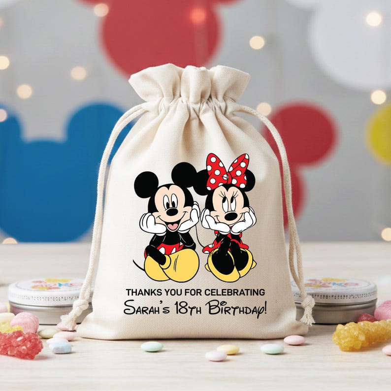May include: A cream-colored drawstring gift bag featuring Mickey and Minnie Mouse. The cartoon characters are in their classic outfits. Text on the bag reads, "THANKS YOU FOR CELEBRATING Sarah's 18th Birthday!"