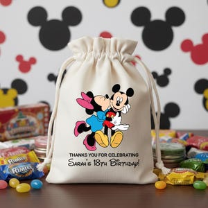May include: A cream-colored drawstring bag featuring Mickey and Minnie Mouse in a loving embrace. The bag has the text "THANKS YOU FOR CELEBRATING Sarah's 18th Birthday!" printed in black. The background has Mickey Mouse head silhouettes.