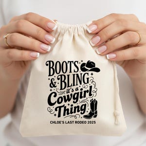 Puede incluir: Una bolsa beige con cordón, con la frase "BOOTS & BLING it's a Cowgirl Thing" en letras negras y un dibujo de un sombrero y una bota de vaquero. El texto "CHLOE'S LAST RODEO 2025" está impreso en la parte inferior.