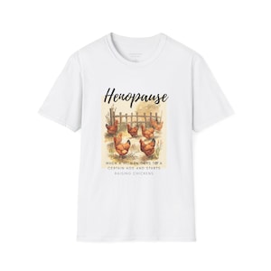 Può includere: T-shirt bianca con la scritta "Henopause" e un'illustrazione ad acquerello di galline in un pollaio. La grafica include il testo: "Quando una donna raggiunge una certa età e inizia ad allevare polli."