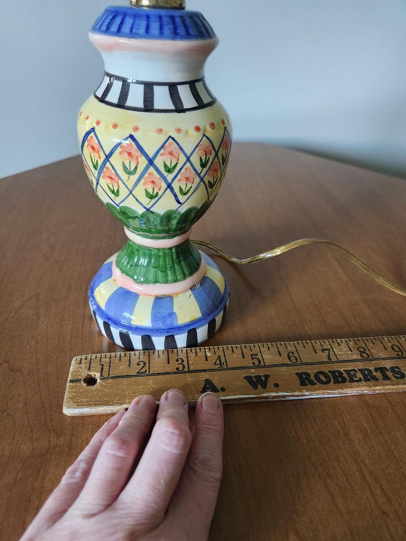 May include: A colorful ceramic table lamp with a painted floral design. The lamp features a blue, yellow, and green base with a matching top. The lamp is approximately 9 inches tall.