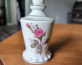 Flacone di profumo vintage in porcellana e ceramica, affusolato, con decorazione a rosa muschio, finiture in argento platino e base smerlata e svasata, ideale come vassoio da toeletta.