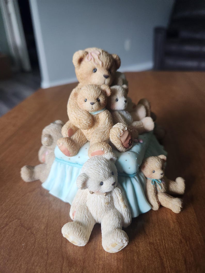 Puede incluir: Figura decorativa con un grupo de osos de peluche. Los osos est&aacute;n en varias poses, algunos sentados y otros tumbados. La figura tiene una base azul claro con lunares blancos. Los osos son de color marr&oacute;n y blanco.