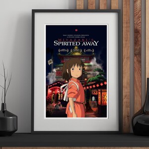 May include: Framed poster of the animated film "Spirited Away." The poster features a young girl in an orange dress standing in front of a detailed building with red lanterns. The film's title and credits are displayed at the top.
