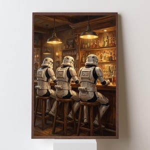 May include: A framed print depicts three Stormtroopers in white armor sitting at a bar. The bar is dimly lit with overhead lights and a shelf of liquor bottles. The artwork has a vintage, painterly style.