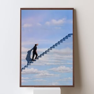 May include: Framed art print featuring a surreal image of a person ascending a staircase that leads into a cloudy blue sky. The artwork has a brown frame and is mounted on a white pedestal.