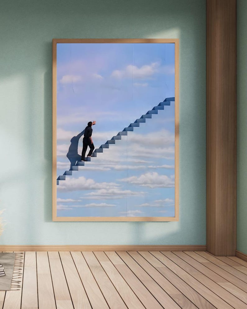 May include: A framed art print depicts a surreal scene of a person ascending a staircase that leads into a blue sky filled with clouds. The artwork is set in a room with light green walls and a wooden floor.