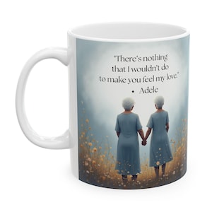 May include: White ceramic mug featuring an illustration of two women holding hands in a field of flowers. The mug has the quote "There's nothing that I wouldn't do to make you feel my love." by Adele.