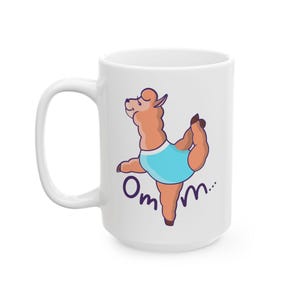 May include: White ceramic mug featuring a cartoon llama in a yoga pose, wearing a blue outfit. The mug has the text "Om m..." in purple. The mug has a large handle.