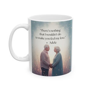 May include: White ceramic mug featuring a romantic scene of an elderly couple holding hands, with a quote from Adele: "There's nothing that I wouldn't do to make you feel my love." The mug has a white handle and a light-colored background.