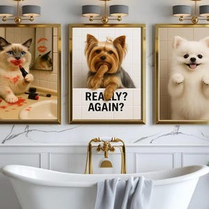 May include: Three framed animal portraits hang above a bathtub. The portraits feature a cat with lipstick, a dog with the text "REALLY? AGAIN?", and a fluffy white dog. The frames have gold trim, and the bathroom has a marble wall.