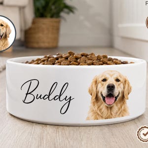 May include: A white ceramic pet bowl filled with brown dry kibble. The bowl features a custom graphic of a golden retriever and the name Buddy written in black cursive script. A circular inset shows the same dog portrait in the upper left corner.