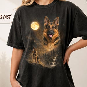 Könnte beinhalten: Schwarzes T-Shirt mit einem Design eines Deutschen Schäferhundes. Die Grafik zeigt einen Vollmond, einen Wald und einen Wasserfall. Das Shirt hat den Text "SHIPS FAST" auf der linken Seite.