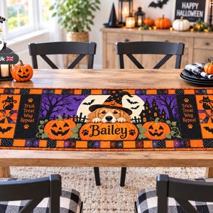 Könnte beinhalten: Ein rechteckiger Halloween-Tischläufer mit einer zentralen Illustration eines Golden Retrievers mit Hexenhut hinter einem Kürbis mit der Aufschrift Bailey. Das Design zeigt orangefarbene Kürbisse, schwarze Katzen, Geister, Fledermäuse und den Text Trick Treat Wag Repeat.