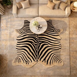 May include: A beige and black zebra-print rug with a unique shape, placed on a neutral-colored rug. The rug is under a round marble coffee table and a beige sofa with matching pillows. The room has a modern, stylish aesthetic.