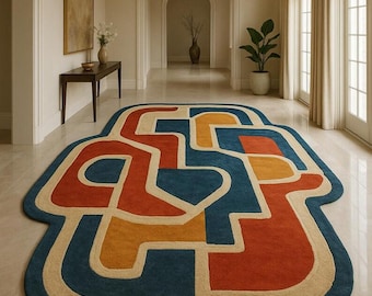 May include: A large, abstract area rug with a bold design. The rug features a blue border with a cream-colored outline, and the interior is filled with geometric shapes in orange, yellow, and blue. The rug is placed in a hallway.