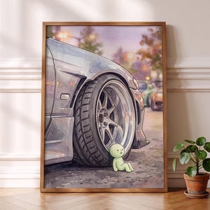 Könnte beinhalten: Ein gerahmter Aquarelldruck, der das Vorderrad und den Kotflügel eines silbernen Sportwagens auf Asphalt zeigt. Eine kleine, hellgrüne Figur mit rundem Kopf sitzt auf dem Boden neben dem Reifen. Der Hintergrund zeigt eine verschwommene Straße.