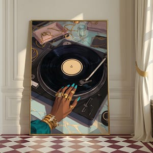 Puede incluir: Una obra de arte enmarcada representa un tocadiscos con un disco de vinilo negro. Una mano con uñas turquesas y joyas de oro descansa sobre el tocadiscos. Otras joyas y accesorios son visibles sobre una superficie azul claro. La obra está en una habitación con ventana y cortinas.