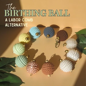 May include: A collection of eleven spherical, textured sensory tools arranged in a circle, each featuring small spikes and a gold-toned metal loop. The text reads: The BIRTHING BALL A LABOR COMB ALTERNATIVE. The colors include blue, yellow, green, brown, and white.