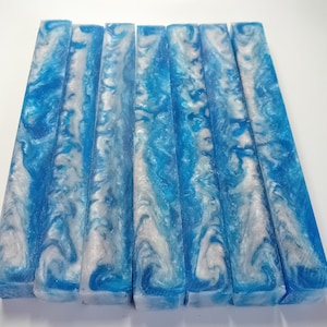 Può includere: Otto blocchi rettangolari con un design marmorizzato. I blocchi presentano un motivo a vortice di bianco e sfumature di blu. I blocchi sono disposti fianco a fianco, mostrando le variazioni di colore e le trame uniche.