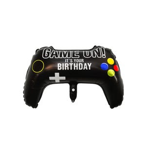 Op de afbeelding: Zwarte ballon in de vorm van een videogamecontroller met de tekst "GAME ON! IT'S YOUR BIRTHDAY" in het wit. De controller heeft gele, blauwe en rode knoppen. Een leuke decoratie voor een verjaardagsfeest.