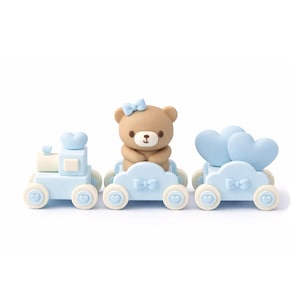 May include: A set of three toy train carriages. The first carriage is light blue with a heart-shaped top. The second carriage has a brown bear with a blue bow. The third carriage has two blue heart shapes. All carriages have heart-shaped wheels.