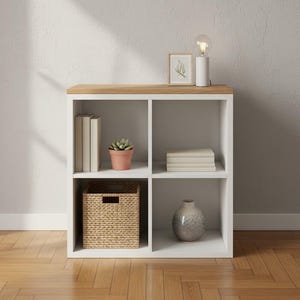 May include: A white cube shelf unit with four compartments. The top is wood-toned. Items in the compartments include books, a potted succulent, a woven basket, a stack of books, and a decorative vase. A small lamp and framed art piece sit on top.