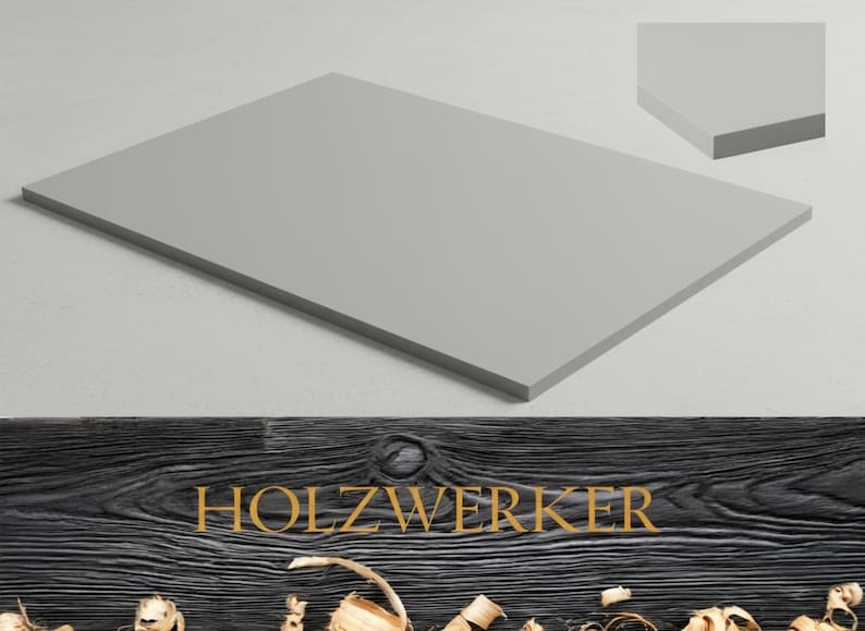 May include: A rectangular, light gray wooden panel with a smooth surface. The panel is displayed on a white background, with a smaller, angled section of the panel visible in the upper right corner. The word "HOLZWERKER" is displayed in gold lettering.