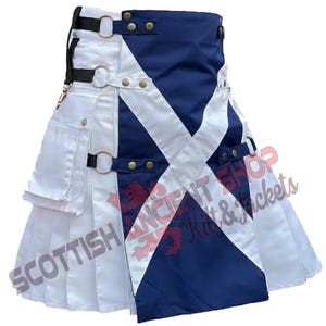 Op de afbeelding: Een witte en marineblauwe kilt met een Schots vlagontwerp. De kilt heeft een geplooide rok, zakken en verstelbare bandjes met metalen hardware. De tekst "Scottish Ancient Shop Kilt & Jackets" is zichtbaar.